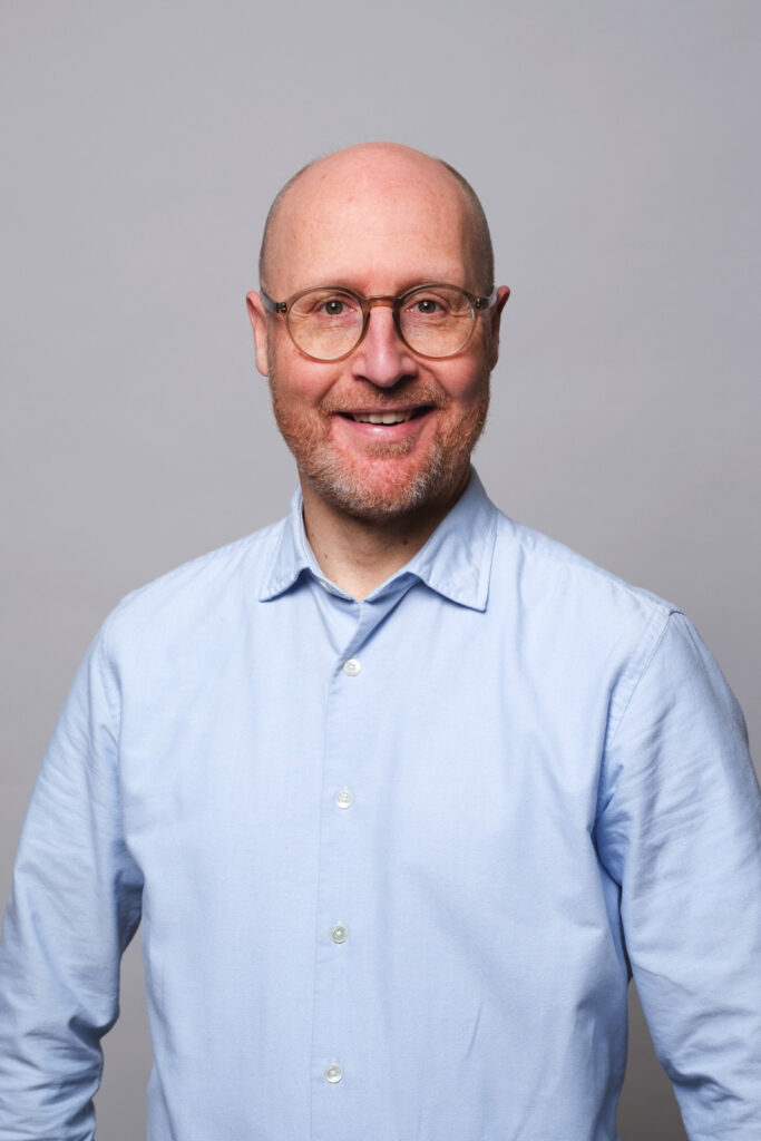 Portraitfoto von Stefan Bucher in hellblauem Hemd, lachend